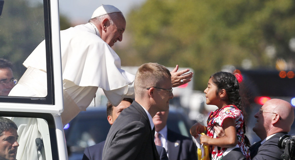 Pope Francis reaches from the popemobile for a child that is brought to him, during a parade in Washington, Wednesday, Sept. 23, 2015. (AP Photo/Alex Brandon, Pool)